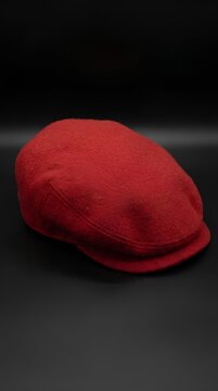 Red vintage flat cap isolated on dark surface.