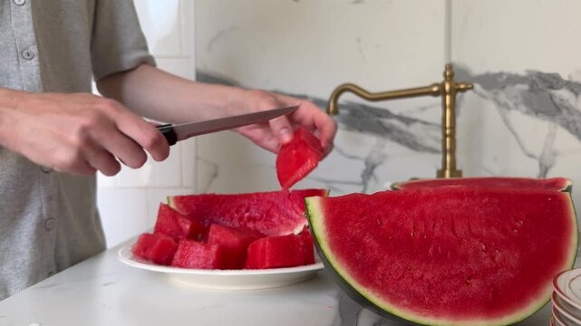 Woman cutting ripe watermelon on kitchen table