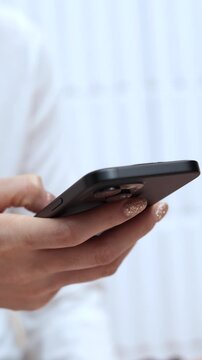 woman holds smart phone in her hands and scrolls through the news feed. Close up of hand uses mobile. point finger on screen, texting text message.	

