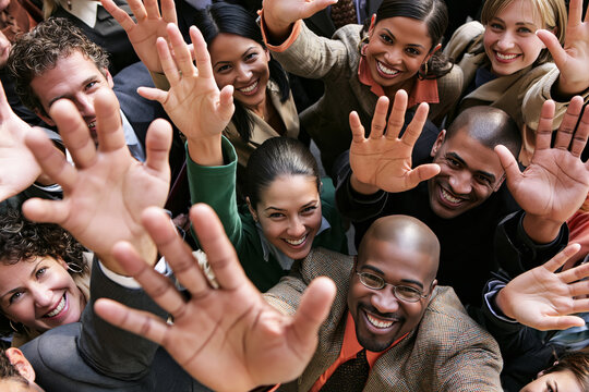 Diverse group of smiling business people reaching hands up toward camera from below expressing teamwork and enthusiasm.