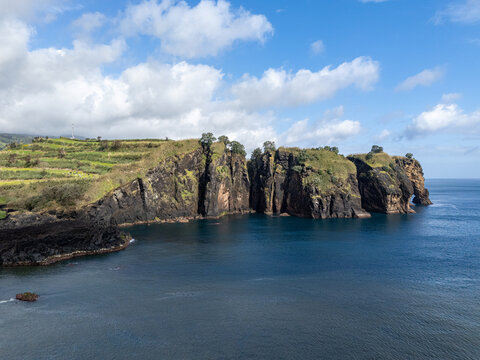 Aerial view of the dramatic volcanic cliffs at Miradouro do Sertao with lush green vegetation and deep blue Atlantic waters, Capelas, Acores, Portugal.