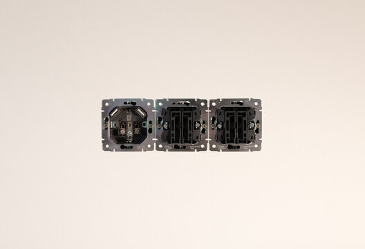 Triple power socket frame installed in residential apartment wall. Black electrical outlet