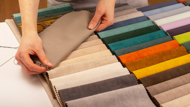 Upholstery fabric swatch catalog selection on workshop table. Interior designer choosing textile