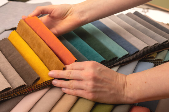 Upholstery fabric swatch selection for sofa restoration order. Hands touching bright yellow tissue