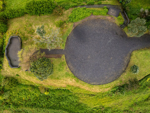 Aerial view of the circular Miradouro de Santa Iria viewpoint surrounded by lush green vegetation and trees in Porto Formoso, Acores, Portugal.