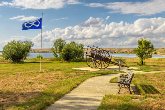 Historic Fur Trade Red River Cart beside Blue Metis Flag on the Shore of Diefenbaker Lake, Saskatchewan Landing Provincial Park, Canada