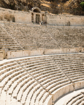 Amman, Jordan - 05 September 2023: View of the historic Roman Theater with its ancient stone seating tiers and arched entrance under a clear sky.