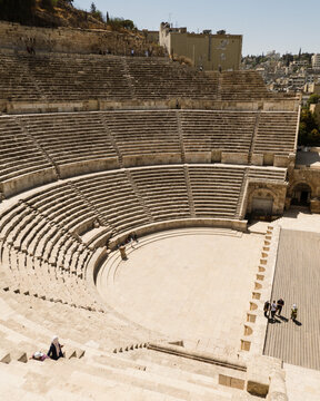 Amman, Jordan - 05 September 2023: View of the Roman Theater with its ancient stone seating, stage area, and visitors exploring the historic site under a clear sky.