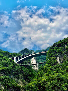 A dramatic double‑bridge scene spans a steep mountain canyon along the G348 Three Gorges Tourist Highway in Xiling Gorge.
