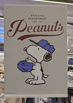 Vista de cerca de un cartel de publicidad con Snoopy de Peanuts Athletic Department since 1950, con gorra y guantes de b&eacute;isbol, en tienda de ropa de Madrid, Espa&ntilde;a, 6 de junio de 2026	