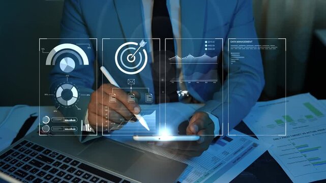 Businessman using a tablet at a desk with holographic digital charts animation on the screen, Hologram business reports and data analytics finance and planning in a modern office