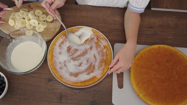 Mother and daughter bake together: close-up of cake, sliced bananas, blueberries, and batter in glass bowl, 25 fps