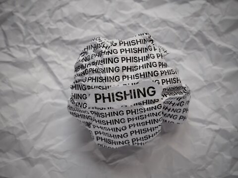 Crumpled paper ball with words Phishing on a crumpled white paper background.