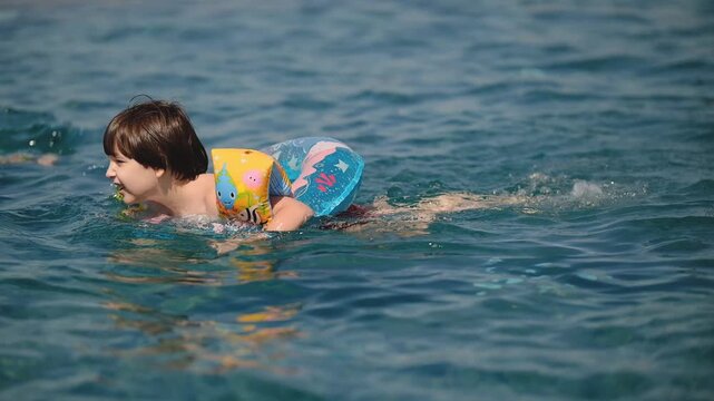 Cute Little Boy Swimming with Inflatable Ring and Armbands in Pool