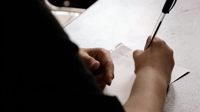 Close Up Of Young Hands Writing Notes Or Letter On Paper At Desk - 4K