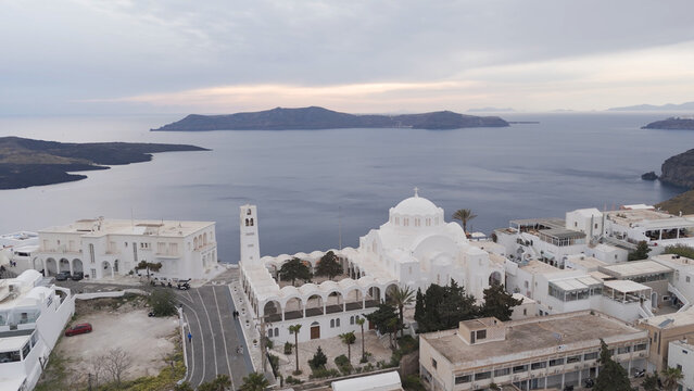 Aerial view of the Orthodox Metropolitan Cathedral in Fira with its white domes and arches overlooking the Aegean Sea in Fira, Greece.