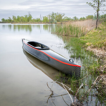 decked touring canoe with carbon fiber hull and rudder at a shore of Horsetooth Reservoir - early spring scenery of Colorado foothills