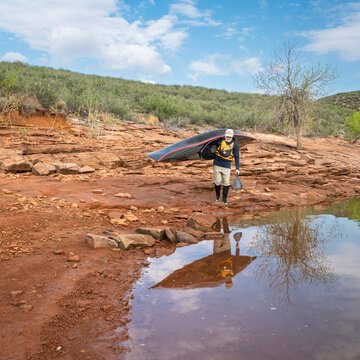 senior paddler is launching his decked touring canoe on shore of Horsetooth Reservoir - early spring scenery of Colorado foothills