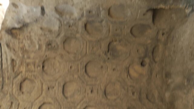 Handheld shot of an intricately carved sandstone ceiling inside the ancient cave city of Uplistsikhe, Georgia. The stone texture reveals historic geometric craftsmanship of the ruins.