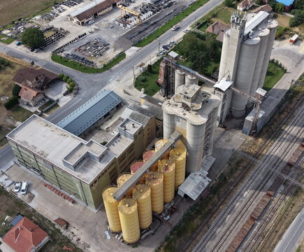 Aerial view of an industrial grain mill complex featuring tall concrete silos and yellow storage tanks situated near railway tracks in Smederevo, Podunavlje District, Serbia.