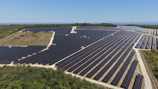 Aerial view of the 9.9 MW solar power plant featuring rows of photovoltaic panels surrounded by green trees and rural landscape in Lapovo, Sumadija District, Serbia.