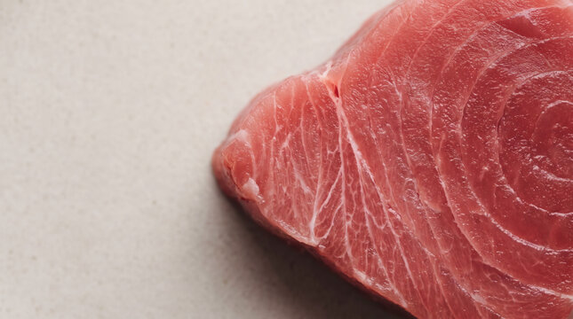Macro view of fresh raw red tuna steak showing detailed meat texture and marbling for gourmet cooking