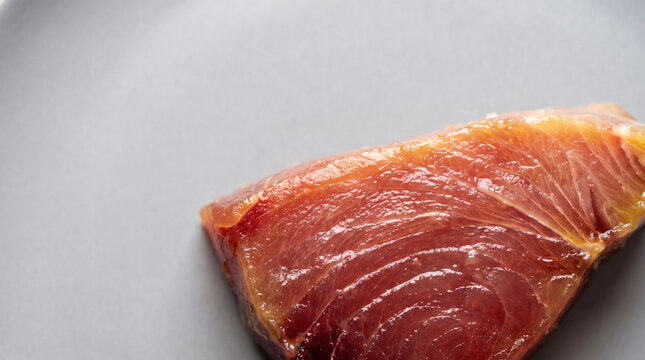 Fresh raw yellowfin tuna saku block texture on a grey ceramic plate for sushi preparation