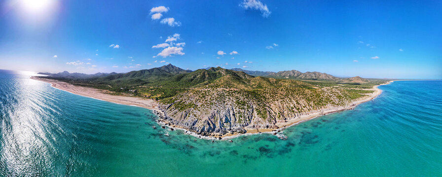 Aerial view of Parque Nacional Cabo Pulmo featuring turquoise waters, rocky cliffs, and lush hills along the coastline in Cabo Pulmo, Baja California Sur, Mexico.