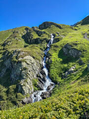 Naklejka premium Mountain waterfall on green slope in Les Contamines-Montjoie, France