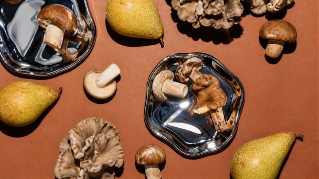 Autumn flat lay with fresh pears and mushrooms on chrome plates. Culinary composition for harvest thanksgiving festival.