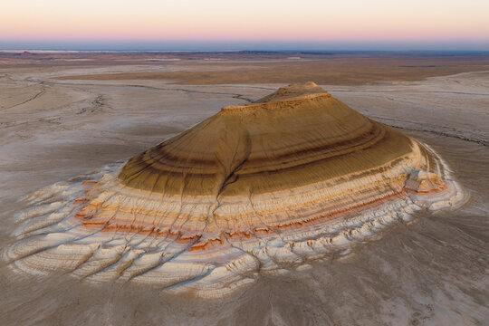 Aerial view of Gora Bokty, a unique striped mountain rising from the arid desert landscape with layered sedimentary rock formations in Karakiya District, Mangystau Region, Kazakhstan.