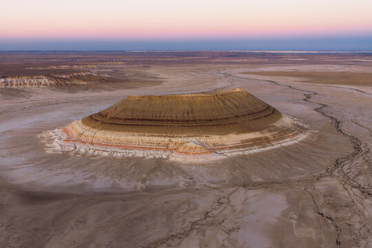 Aerial view of Gora Bokty featuring distinct sedimentary rock layers rising from the arid desert plains of the Karakiya District, Mangystau Region, Kazakhstan.
