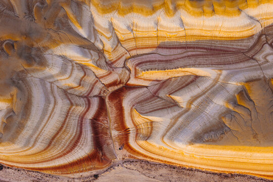 Aerial view of Tiramisu Hills showcasing vibrant, multi-colored sedimentary layers, intricate erosion patterns, and textured desert terrain in Kyzylkum, Mangystau Region, Kazakhstan.