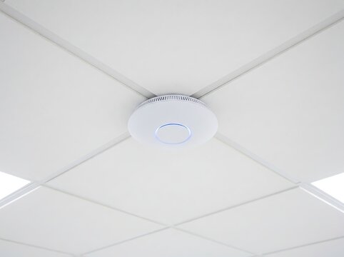 White ceiling mounted access point with blue LED ring providing wireless internet connectivity for office spaces.