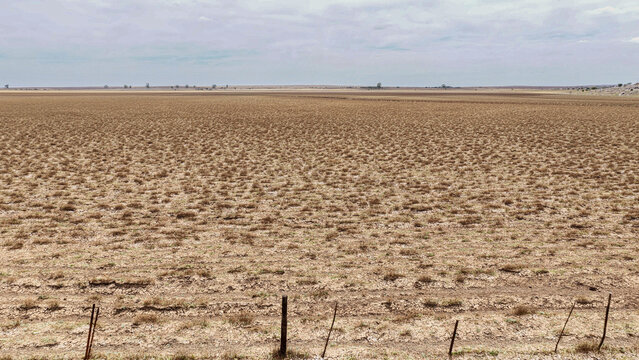 Aerial view of the vast arid landscape of the Karoo with sparse dry vegetation and flat terrain under an overcast sky in Beaufort West, Western Cape, South Africa.