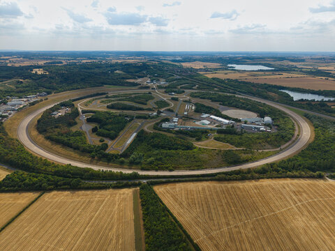 Aerial view of Millbrook Proving Ground with its circular test track surrounded by lush greenery and agricultural fields in Bedford, England, United Kingdom.