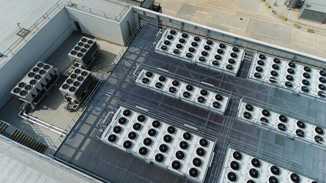 Aerial view of multiple industrial ventilation cooling units, heat exchangers, and HVAC fans arranged in rows on a flat commercial rooftop in Luton, England, United Kingdom.