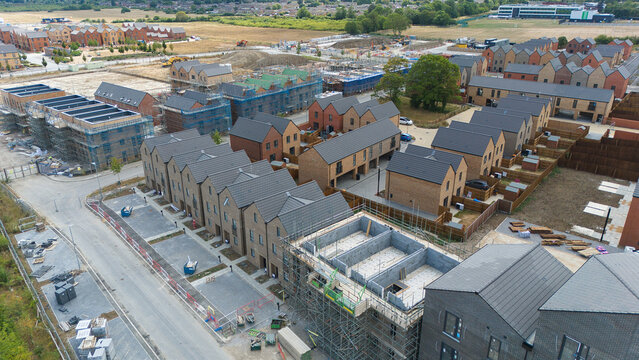 Aerial view of new residential housing construction with rows of brick houses, scaffolding, and ongoing development in a suburban area in Luton, England, United Kingdom.