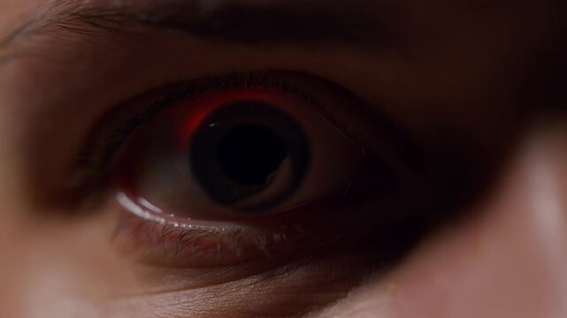 Open human eye in extreme closeup under warm low light with a stationary gaze