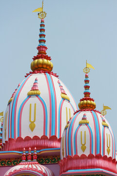 Close-up view of sacred Vaishnava temple spires and golden domes decorated with the Tilaka symbol against the sky