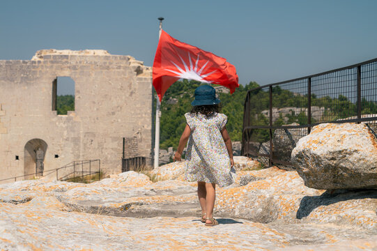 Fillette au chapeau marchant vers un drapeau au ch&acirc;teau des Baux-de-Provence