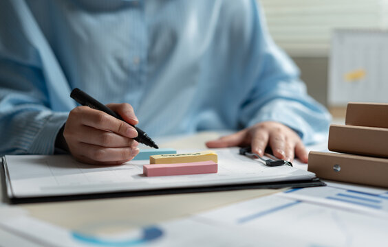 Business professional writing on planning documents with a marker at an office desk, organizing tasks, reviewing reports and developing strategy for project management, productivity and workflow.