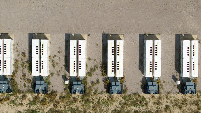 Aerial view of BESS Battery energy park near the M1 motorway with rows of white energy storage containers and electrical equipment in Sundon, England, United Kingdom.