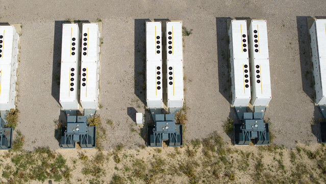 Aerial view of the BESS Battery energy park near the M1 motorway, featuring rows of white battery storage containers and transformers on a gravel site in Sundon, England, United Kingdom.