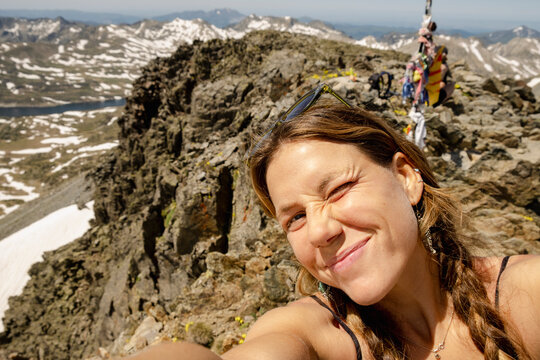 Woman taking winking summit selfie in the Pyrenees mountains