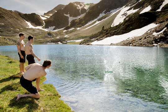 Men skipping stones on alpine lake during Pyrenees hike