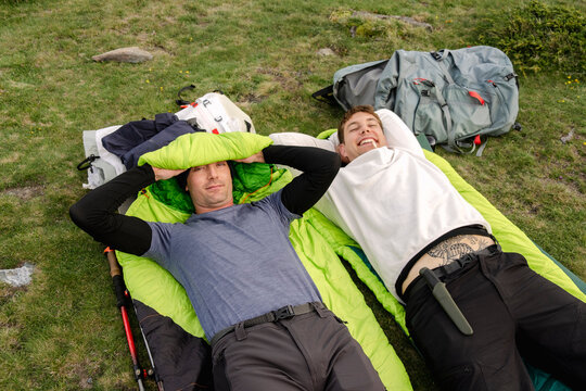 UGC Men laughing on sleeping mats at alpine camp in the Pyrenees