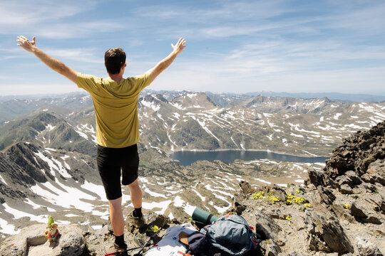 Man celebrating on Pic Carlit summit with French Pyrenees lake view