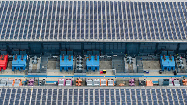 Aerial view of a data center featuring extensive rooftop solar panels and rows of industrial HVAC server cooling units in Hemel Hempstead, England, United Kingdom.