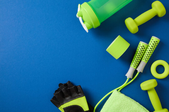 Green fitness accessories arranged on dark blue background.